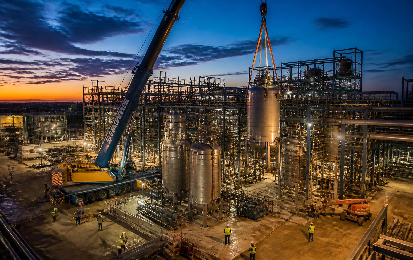 Crane lifting equipment during installation at an industrial plant at dusk